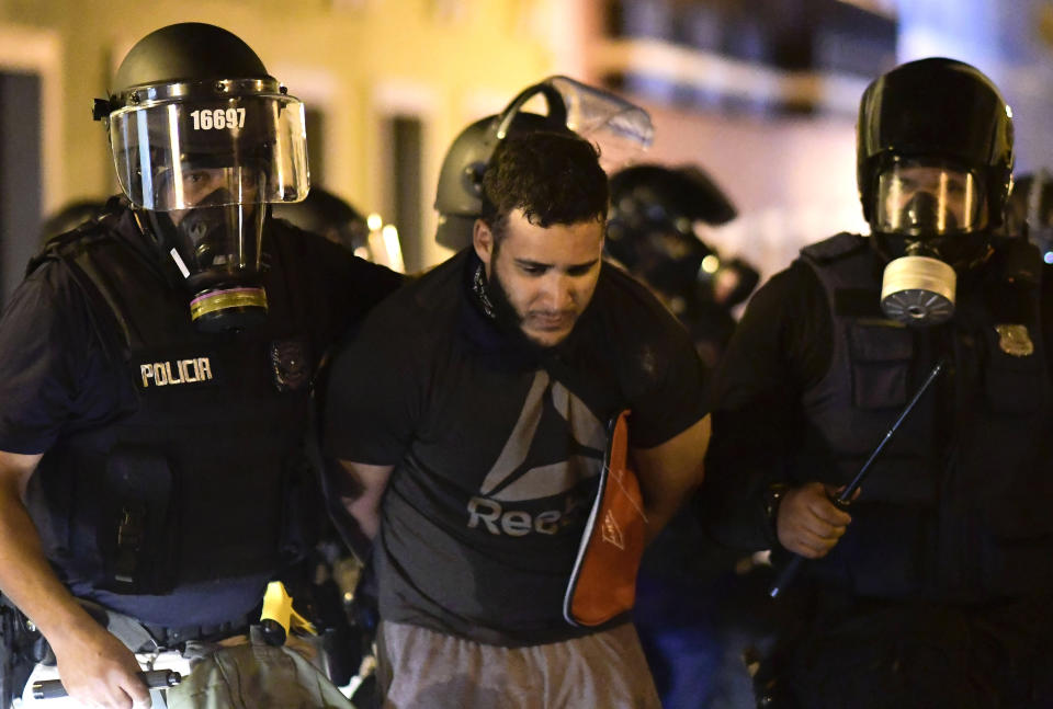 Police arrest a demonstrator during clashes demand the resignation of Gov. Ricardo Rossello in San Juan, Puerto Rico, Monday, July 22, 2019. Protesters are demanding Gov. Ricardo Rossello step down following the leak of an offensive, obscenity-laden online chat between him and his advisers that triggered the crisis. (AP Photo/Carlos Giusti)