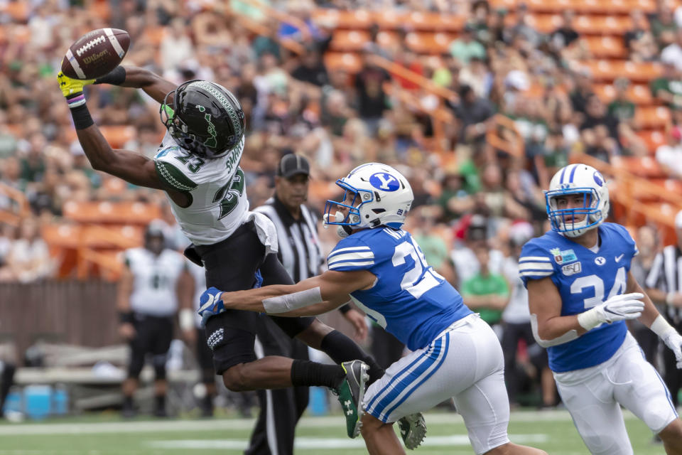 The football is just out of reach of Hawaii wide receiver Jared Smart (23) as BYU defensive back Shamon Willis (29) and linebacker Kavika Fonua (34) defend during the first half of the Hawaii Bowl NCAA college football game Tuesday, Dec. 24, 2019, in Honolulu. (AP Photo/Eugene Tanner)