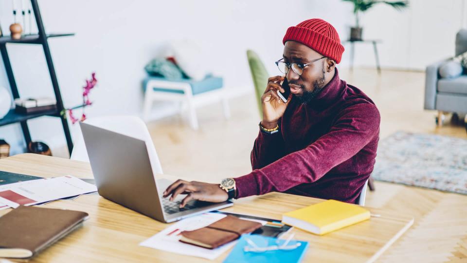 man on phone while using laptop