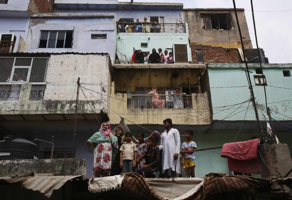 Local residents watch the site of a collapsed building in New Delhi