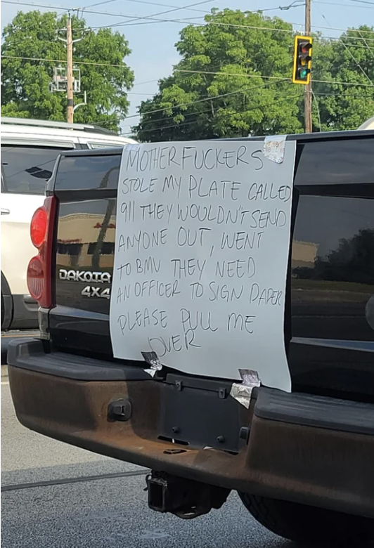 A truck is missing its back license plate, but there's a taped sign in its place