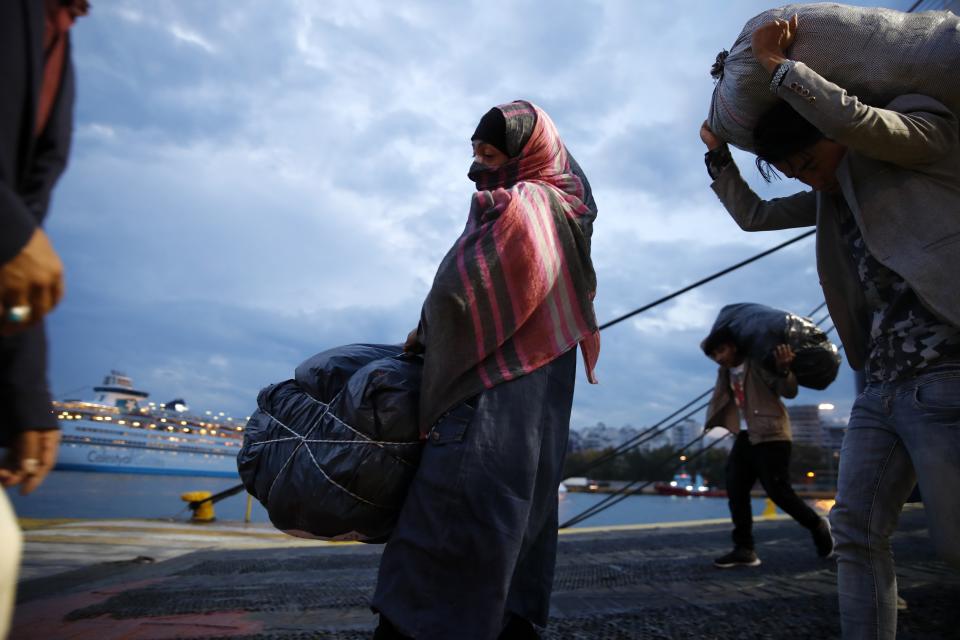 Migrants carry their belongings as they arrive from Lesbos island to the port of Piraeus, near Athens, Monday Oct. 7, 2019. In the last 24 hours 668 refugees and migrants have been transferred to mainland Greece from five Greek islands as authorities have accelerated efforts to ease over crowding in the camps. (AP Photo/Thanassis Stavrakis)