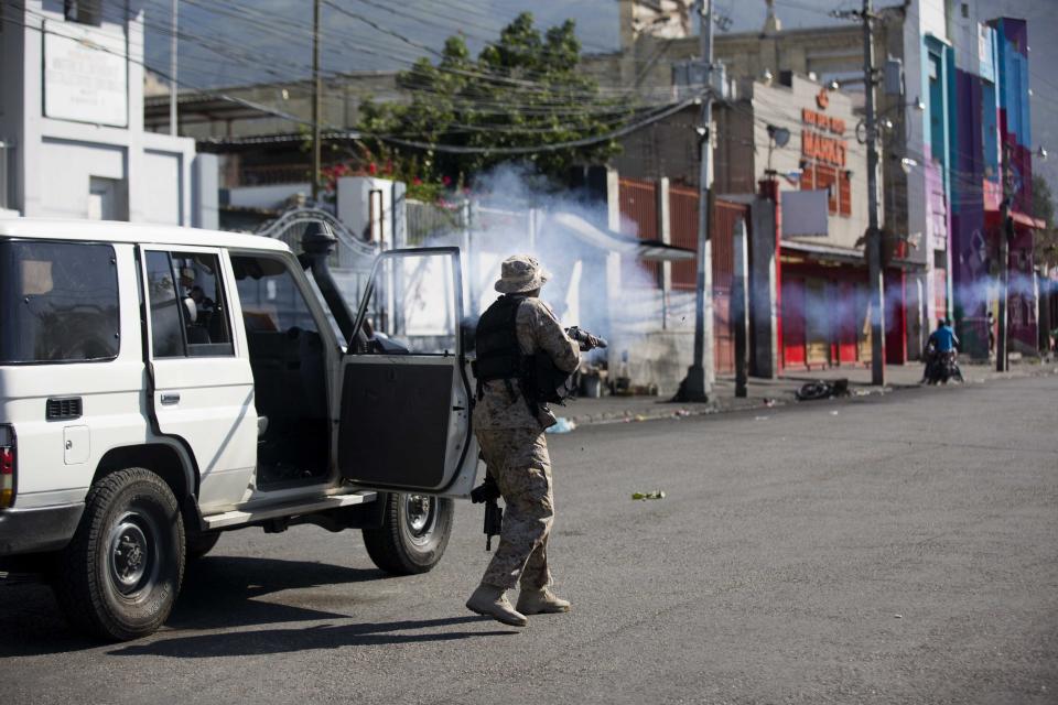 A police officer fires tear gas at demonstrators during a protest to demand the resignation of President Jovenel Moise and demanding to know how Petro Caribe funds have been used by the current and past administrations, in Port-au-Prince, Haiti, Saturday, Feb. 9, 2019. Much of the financial support to help Haiti rebuild after the 2010 earthquake comes from Venezuela's Petro Caribe fund, a 2005 pact that gives suppliers below-market financing for oil and is under the control of the central government. (AP Photo/Dieu Nalio Chery)