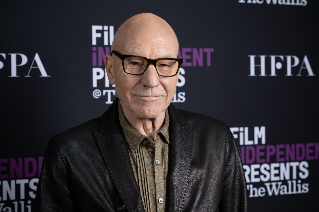 Sir Patrick Stewart, wearing black frame glasses, a brown collared shirt and a leather jacket, gives a small smile as he attends the Film Independent At The Wallis Presents An Evening With...Sir Patrick Stewart event at the Wallis Annenberg Center for the Performing Arts