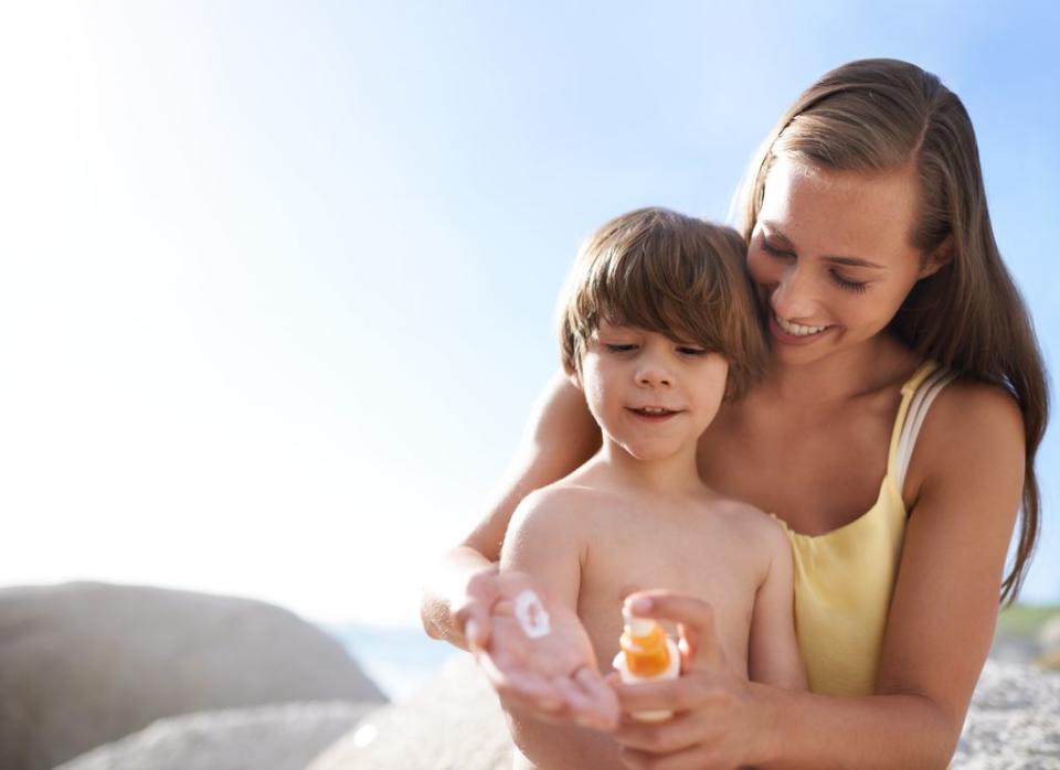 Madre poniendo crema solar a su hijo