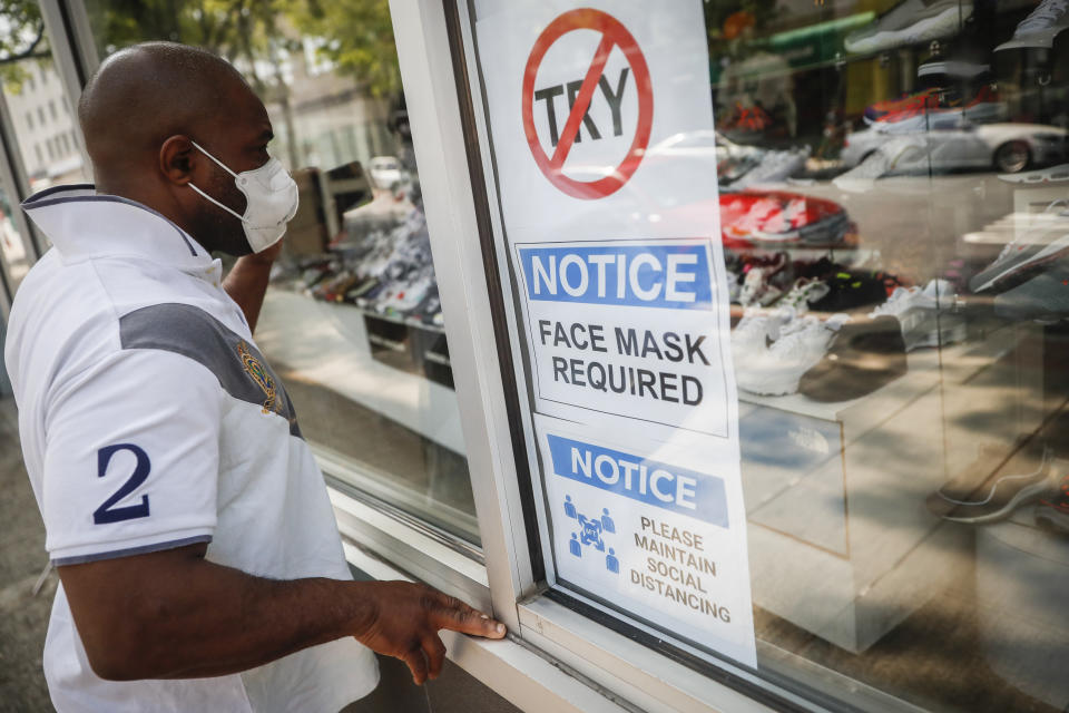 A pedestrian browses the display window at The Loop fashion and shoe store as businesses slowly begin to reopen after social distancing restrictions shuttered storefronts nationwide, Tuesday, May 26, 2020, in Yonkers, N.Y. (AP Photo/John Minchillo)