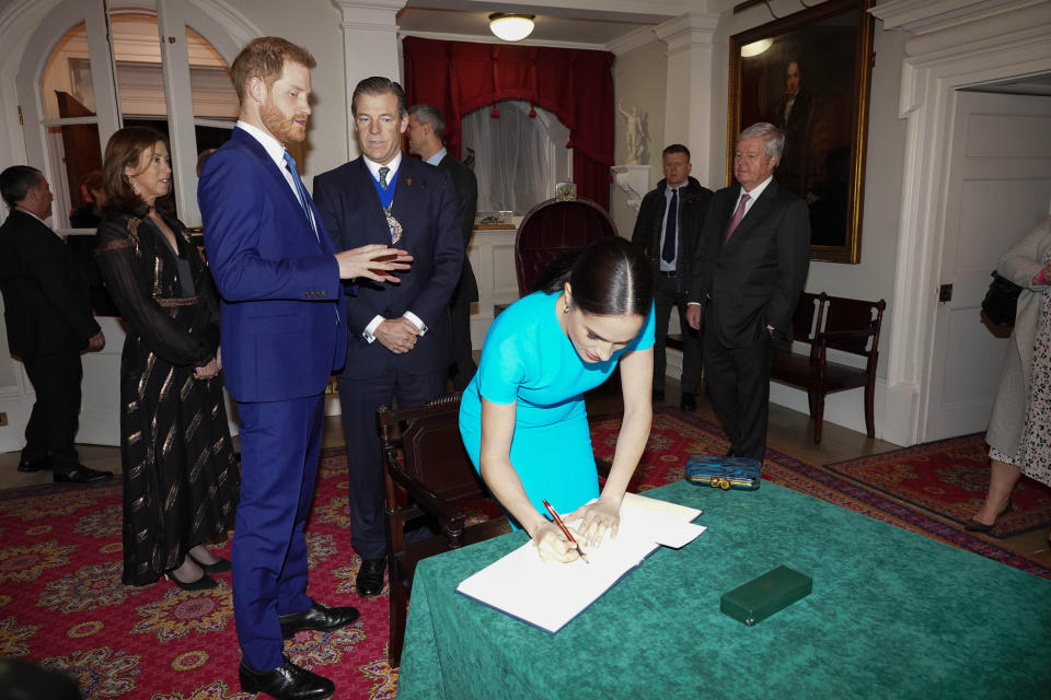 The Duke and Duchess of Sussex sign the book at the awards. (Press Association)