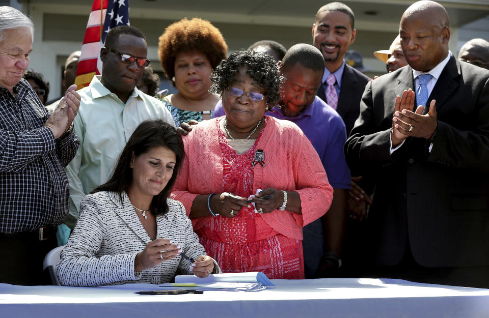 FILE - With North Charleston Mayor Keith Summey, at left, and South Carolina Senator Gerald Malloy, at right, South Carolina Gov. Nikki Haley, surrounded by the family of Walter Scott including, from left to right, brother Rodney Scott, mother Judy Scott, and brother Anthony Scott, signs a bill into law to equip all South Carolina police officers with body cameras June 10, 2015, in North Charleston, S.C. (Grace Beahm/The Post and Courier via AP, File)