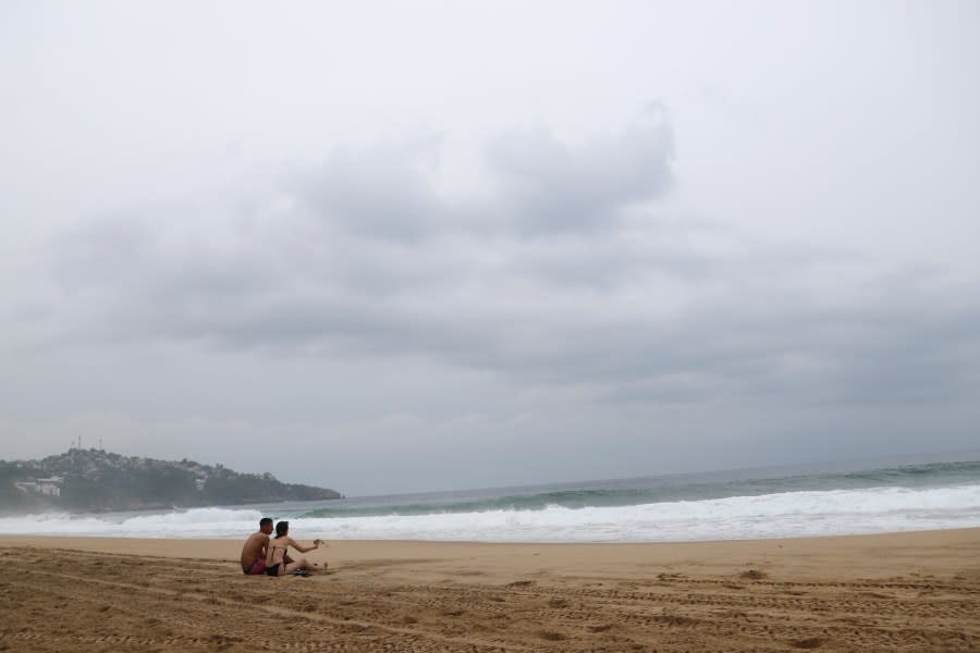 Tourists sit on the beach in Acapulco, Mexico, Tuesday, Oct. 24, 2023. Hurricane Otis has strengthened from tropical storm to a major hurricane in a matter of hours as it approaches Mexico’s southern Pacific coast where it was forecast to make landfall near the resort of Acapulco early Wednesday. (AP Photo/Bernardino Hernandez)