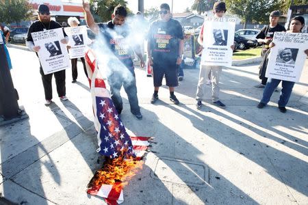 Activists burn a U.S. flag with posters of Alton Sterling and Philando Castile as they protest on the corner of Florence Ave and Normandie Ave against the police shootings that lead to two deaths in Louisiana and Minnesota, respectively, in Los Angeles, California, July 7, 2016. REUTERS/Patrick T. Fallon