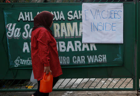 A resident who was displaced due to fighting between government soldiers and the Maute militant group, carries plastic containers with water towards an evacuation centre in Marawi City in southern Philippines May 28, 2017. REUTERS/Erik De Castro