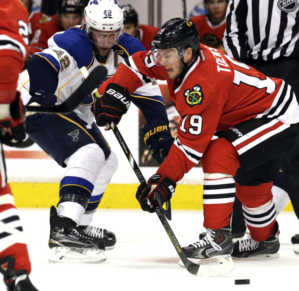 Chicago Blackhawks' Jonathan Toews (19) passes the puck against St. Louis Blues' David Backes (42) during the first period in Game 6 of a first-round NHL hockey playoff series in Chicago, Sunday, April 27, 2014. The Blackhawks won 5-1. (AP Photo/Nam Y. Huh)