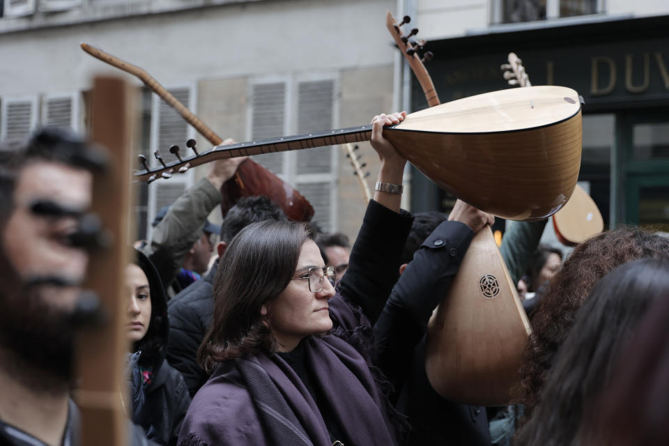 Kurdish activists hold music instruments at the site where three women Kurdish activists were found shot dead in 2013, Monday, Dec. 26, 2022 in Paris. A 69-year-old Frenchman is facing preliminary charges of racially motivated murder, attempted murder and weapons violations over last Friday's shooting, prosecutors said. The shooting shocked and infuriated the Kurdish community in France. ( AP Photo/Lewis Joly)