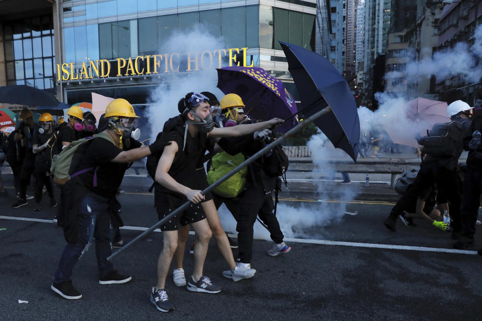 FILE - In this July 28, 2019, file photo, protesters use umbrellas to shield themselves from tear gas fired by policemen as they face off on a streets in Hong Kong. China’s central government has dismissed Hong Kong pro-democracy protesters as clowns and criminals while bemoaning growing violence surrounding the monthslong demonstrations. (AP Photo/Vincent Yu, File)