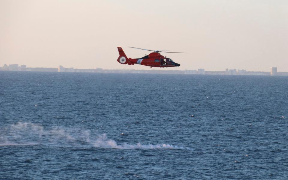 A US Coast Guard helicopter flies over a debris field during recovery efforts of the Chinese spy balloon shot down on Saturday - US Navy via AP