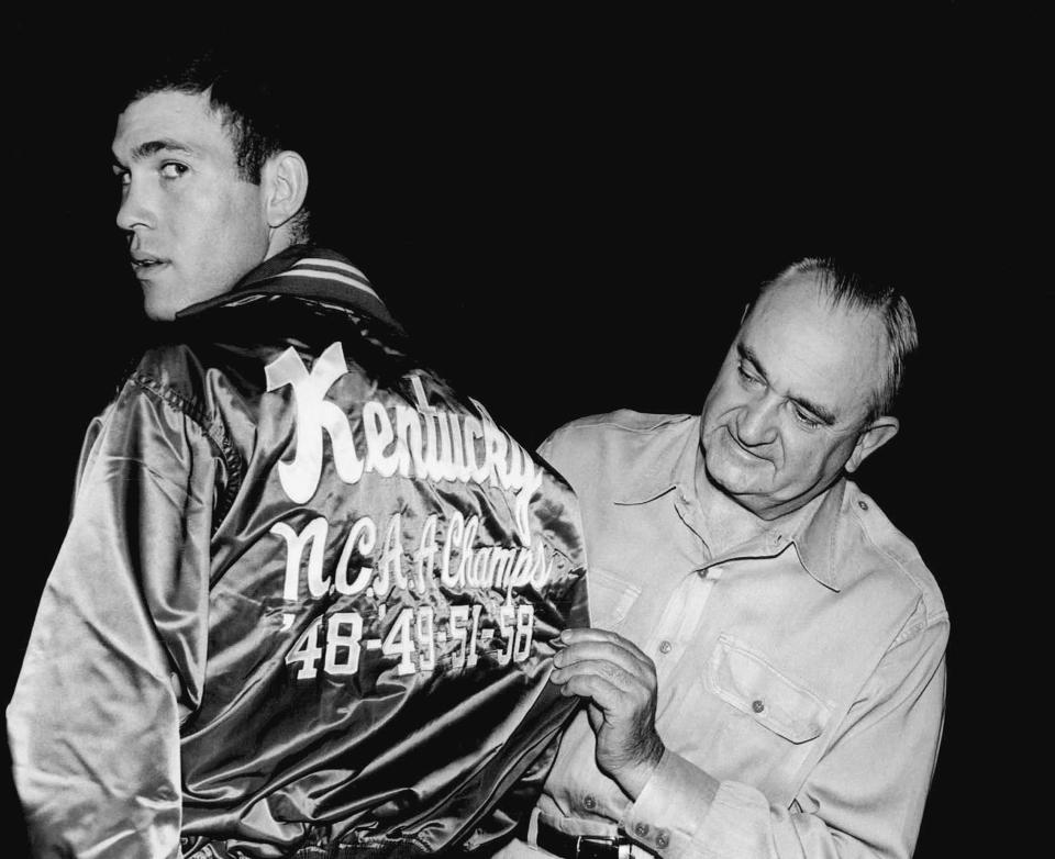 FILE - University of Kentucky coach Adolph Rupp looks over the jacket worn by Johnny Cox, December 1, 1958, at the Lexington, Ky. campus. When the first AP Top 25 men's college basketball poll was published on Jan. 17, 1949, Saint Louis was installed at No. 1 ahead of mighty Kentucky. (AP Photo/File)