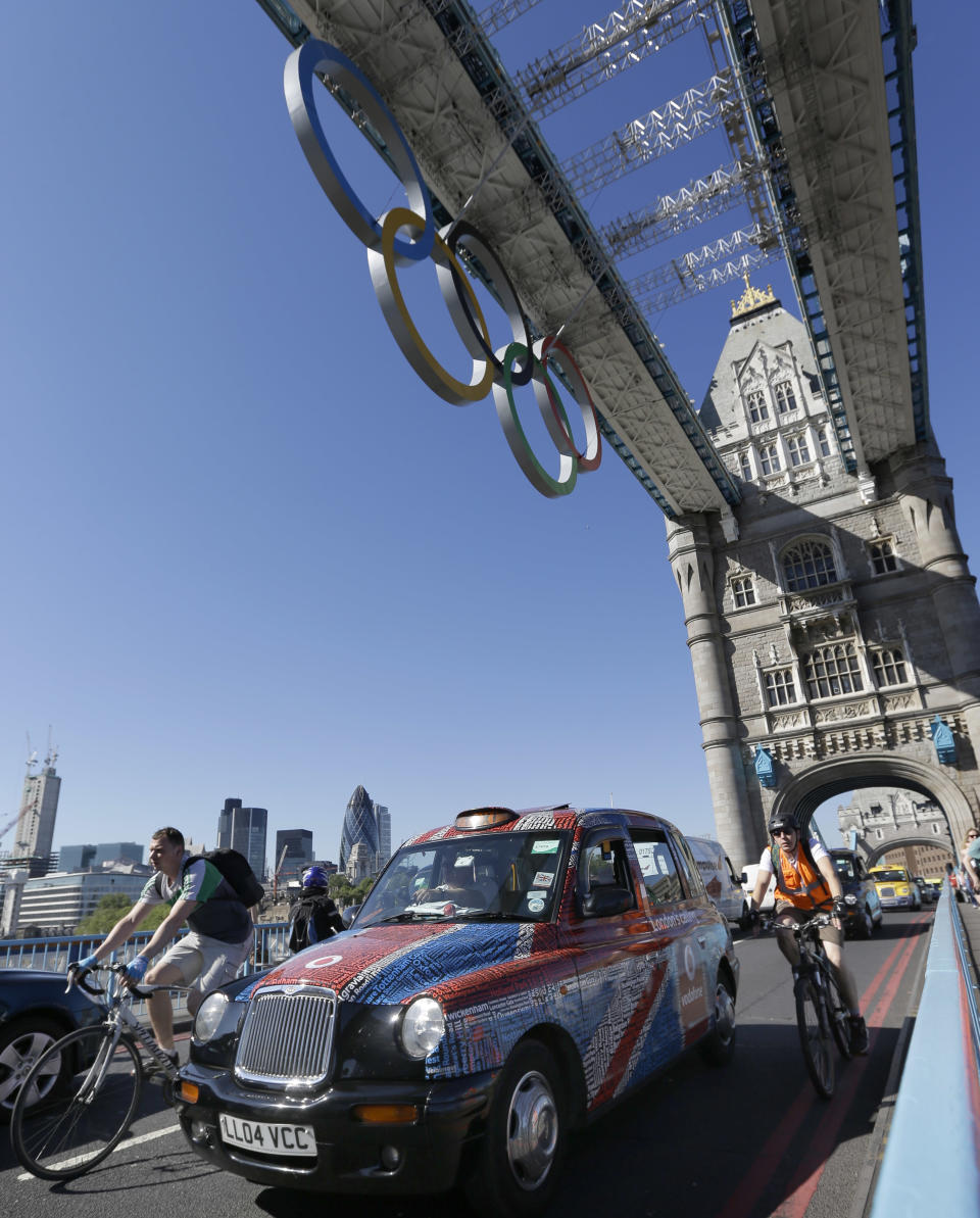 Taxis drive slowly in protest across Tower Bridge in London, Monday, July 23, 2012. The traditional London taxis were holding a protest against not being allowed to drive in the Olympic Lanes once they come into force on Wednesday, July 25. (AP Photo/Kirsty Wigglesworth)