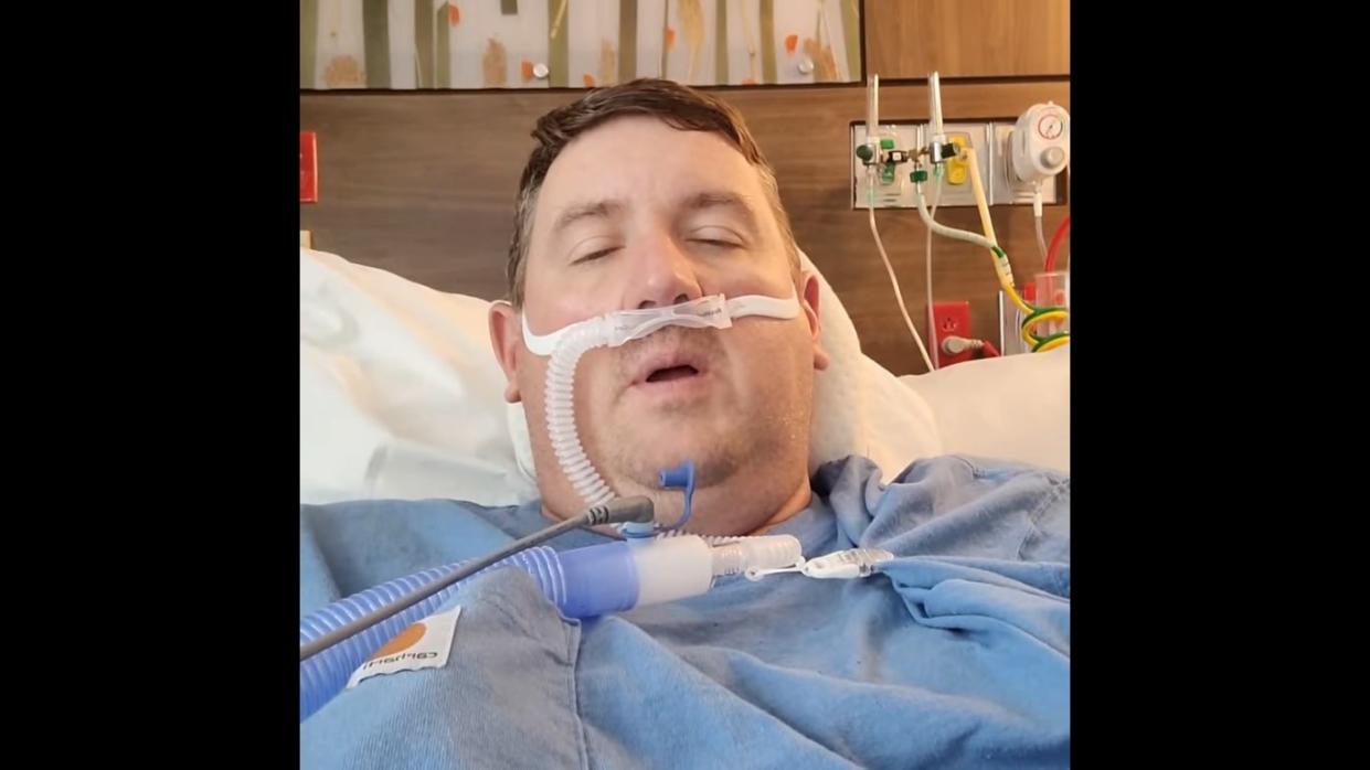 Travis Campbell from Virginia, seen in a hospital bed, urges people to get vaccinated and stop believing in “stupid conspiracies