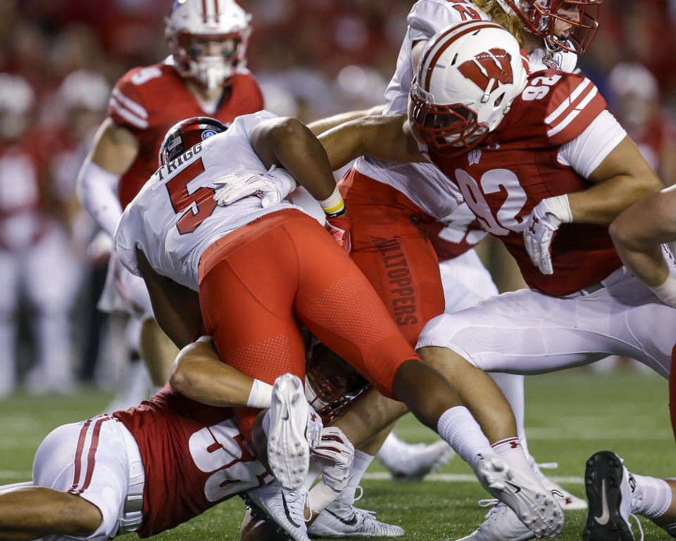 Wisconsin's Zack Baun, bottom, and Matt Hennigsen (92) tackle Western Kentucky running back Marquez Trigg during the first half of an NCAA college football game Friday, Aug. 31, 2018, in Madison, Wis. (AP Photo/Andy Manis)