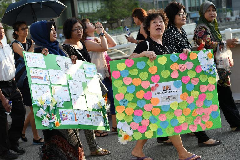 Two mourners hold placards with condolence messages as members of the public queue to pay their respects to Singapore's late former prime minister Lee Kuan Yew at Parliament House where he will lie in state for public viewing on March 25, 2015