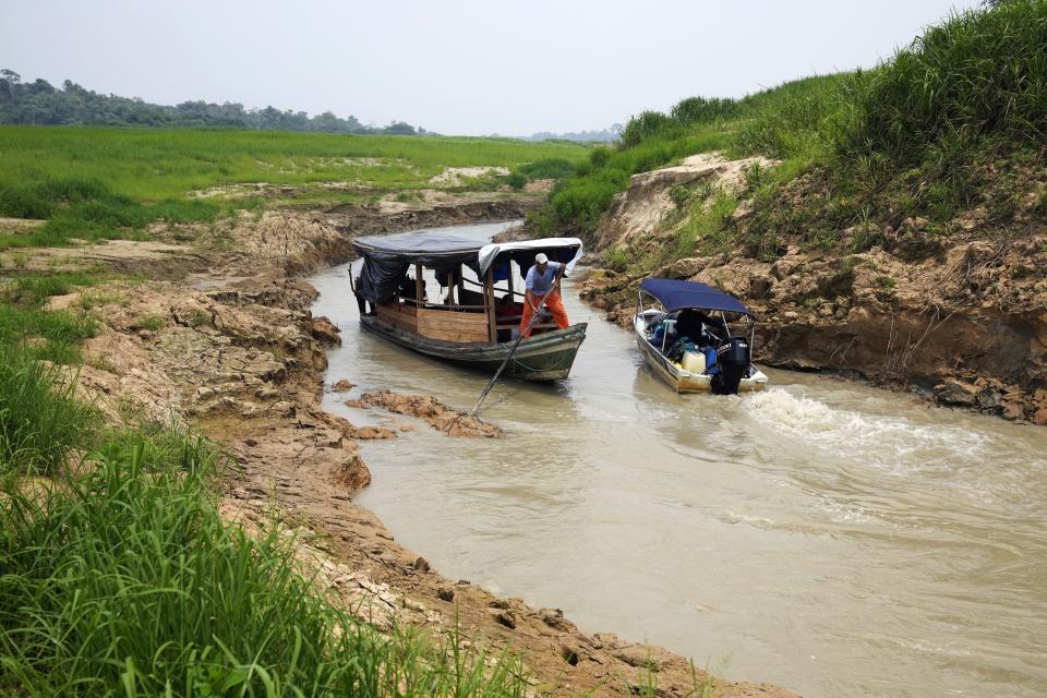 Boats navigate a river in Carauari, Brazil, Wednesday, Sept. 7, 2022. A Brazilian non-profit has created a new model for land ownership that welcomes both local people and scientists to collaborate in preserving the Amazon. (AP Photo/Jorge Saenz)