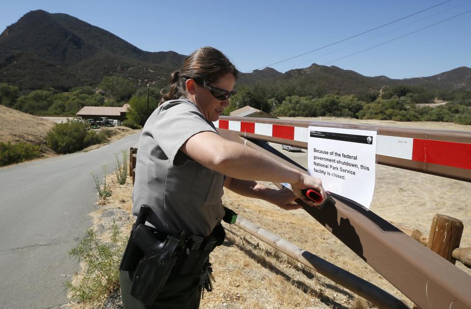 U.S. Park Ranger Melanie Turner posts a sign on the gate of the Paramount Ranch to close the National Park Service site at the Santa Monica mountains in Agoura Hills, California, October 1, 2013. The White House rejected a Republican plan to reopen portions of the U.S. government on Tuesday as the first shutdown in 17 years closed landmarks like the Statue of Liberty and threw hundreds of thousands of federal employees out of work. REUTERS/Lucy Nicholson (UNITED STATES - Tags: POLITICS BUSINESS)