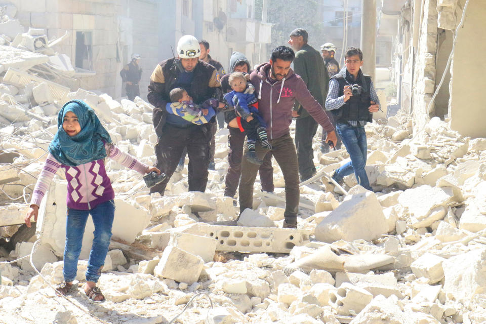 <p>MAR. 19, 2017 – People and a civil defence personnel carry children at a damaged site after an air strike on rebel-held Idlib city, Syria. Photo: Ammar Abdullah/Reuters) </p>