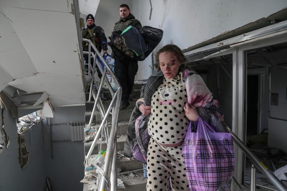 An injured pregnant woman, identified as Podgurskaya in multiple reports,  walks downstairs in a maternity hospital damaged by shelling in Mariupol, Ukraine, Wednesday, March 9, 2022.