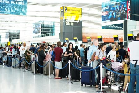 People queue inside Terminal 5 at Heathrow Airport as IT problems caused delays in London