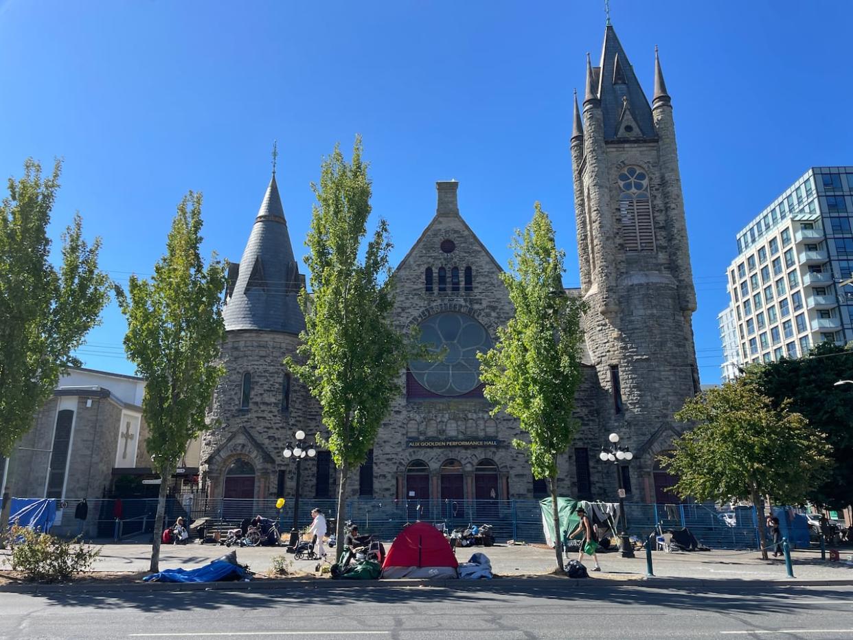 A small encampment is seen in front of the Alix Goolden Performance Hall, part of the Victoria Conservatory of Music, in downtown Victoria in July 2023. (Gregor Craigie - image credit)