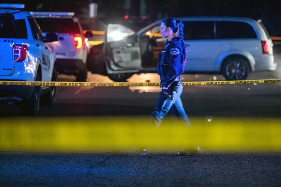 A law enforcement officer walks across the scene of where a Pierce County Sheriff’s deputy shot a man at the Goodwill Plaza parking lot in Parkland, Wash. on Thursday, Jan. 27, 2022. The incident occurred on Pacific Avenue South at Military Road South.