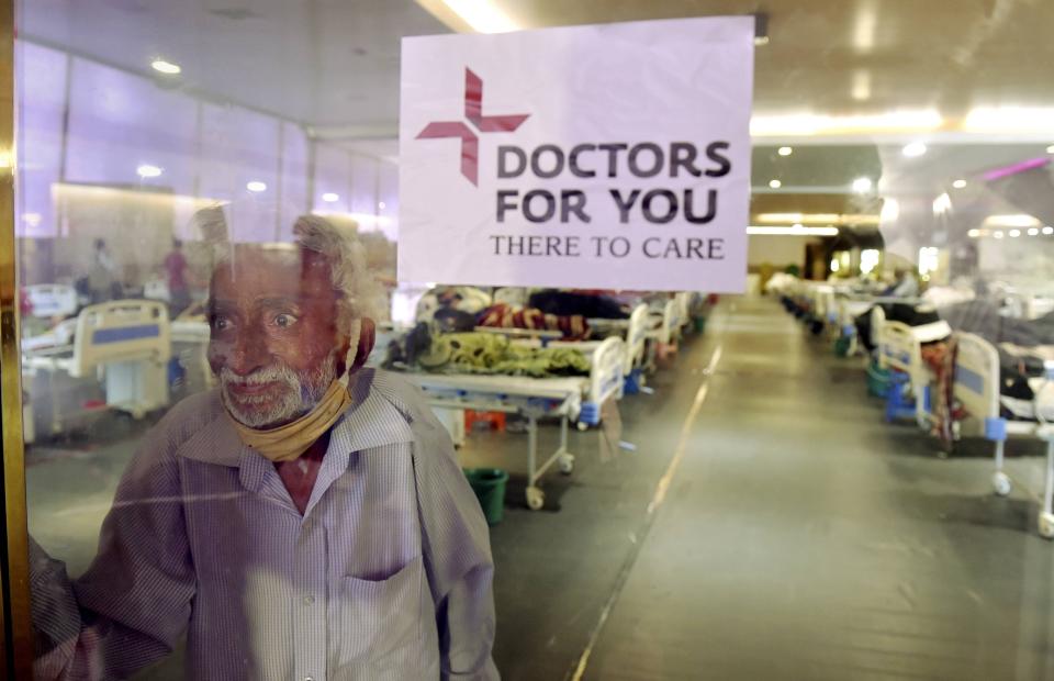 New Delhi: A COVID-19 patient on , Tuesday, 13 April, looks at his family members through a glass barrier at Shehnai Banquet Hall that has been converted into a temporary isolation ward in New Delhi.