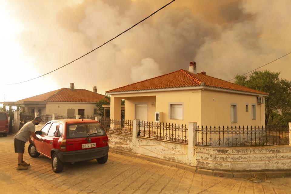 A man goes to a car as flames burn a forest during wildfires in the village of Sykorrahi, near Alexandroupolis town, in the northeastern Evros region, Greece, Wednesday, Aug. 23, 2023. Advancing flames are devouring forests and homes in Greece as wildfires that have killed 20 people are raging. (AP Photo/Achilleas Chiras)