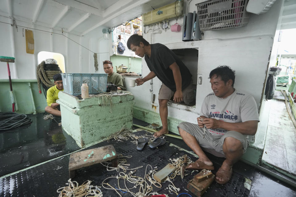 Foreign helpers do some maintenance work on their fishing tools while sitting on their boat docked at the Tomari fishery port in Naha in the main Okinawa island, southern Japan, Thursday, June 1, 2023, as they are not able to go out for fishing while a tropical storm was nearing the Okinawa islands. (AP Photo/Hiro Komae)