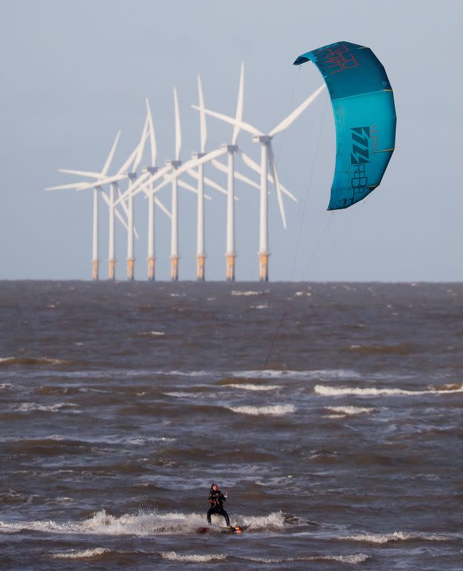 FILE PHOTO: A kitesurfer rides the waves in front of the Burbo Bank offshore wind farm near Wallasey