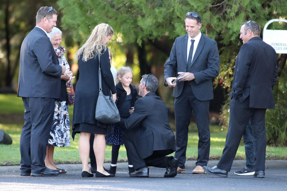 <span>Aaron Cockman (centre, kneeling) is greeted by family and friends outside Bunbury Crematorium. Photo: </span>AAP
