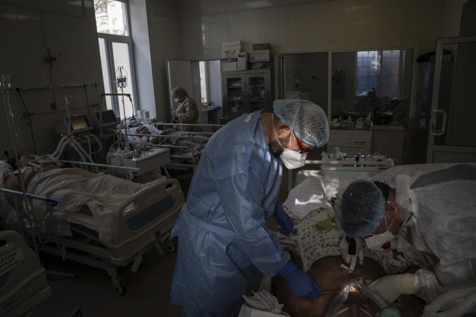 In this handout photo released by UNICEF, Doctors surgery a patient with coronavirus at the ICU department at the city hospital in Kramatorsk, Donetsk region, eastern Ukraine, on Monday, Oct. 18, 2021. Ukraine is suffering through a surge in coronavirus infections, along with other parts of Eastern Europe and Russia. While vaccines are plentiful, there is a widespread reluctance to get them in many countries — though notable exceptions include the Baltic nations, Poland, the Czech Republic, Slovenia and Hungary. (Evgeniy Maloletka, UNICEF via AP)