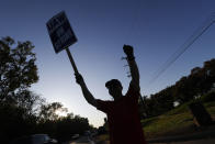 A member of the United Auto Workers cheers on honking cars as he walks the picket line at the General Motors Romulus Powertrain plant in Romulus, Mich., Wednesday, Oct. 9, 2019. Nearly four weeks into the United Auto Workers' strike against GM, employees are starting to feel the pinch of going without their regular paychecks. (AP Photo/Paul Sancya)