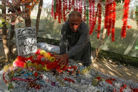 Iqbal Khan puts decorations on his son's grave in a family orchard in Swabi, Pakistan October 24, 2017. Picture taken October 24, 2017. REUTERS/Fayaz Aziz