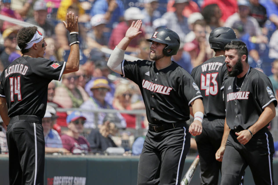 Louisville's Justin Lavey, center, celebrates with teammates after scoring against Vanderbilt on a single by Henry Davis in the fifth inning of an NCAA College World Series baseball game in Omaha, Neb., Sunday, June 16, 2019. (AP Photo/Nati Harnik)