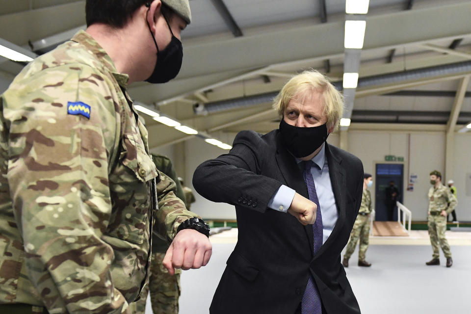 Britain's Prime Minister Boris Johnson elbow bumps a member of the military as he meets troops setting up a vaccination centre in the Castlemilk district of Glasgow, on his one day visit to Scotland, Thursday, Jan. 28, 2021. Johnson is facing accusations that he is not abiding by lockdown rules as he makes a trip to Scotland on Thursday to laud the rapid rollout of coronavirus vaccines across the United Kingdom. (Jeff Mitchell/Pool Photo via AP)