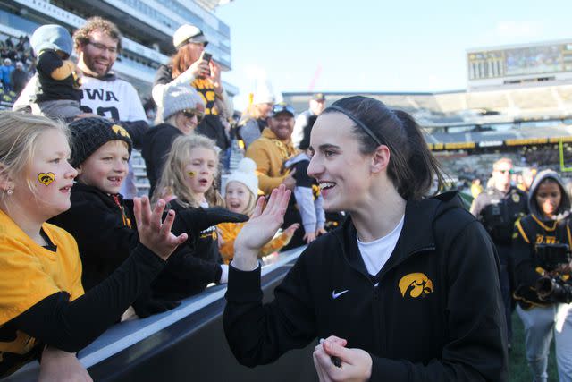 <p>Matthew Holst/Getty </p> Guard Caitlin Clark #22 of the Iowa Hawkeyes interacts with fans after the match-up against the DePaul Blue Demons at Kinnick Stadium during the Crossover at Kinnick event on October 15, 2023 in Iowa City, Iowa.