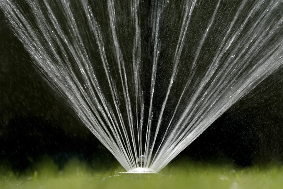 FILE - Water flies from a sprinkler on a lawn in Sacramento, Calif., on July 8, 2021. California Gov. Gavin Newsom threatened Monday, May 23, 2022, to impose mandatory, statewide restrictions on water use if people don't start using less on their own as the drought drags on and the hotter summer months approach. (AP Photo/Rich Pedroncelli, File)