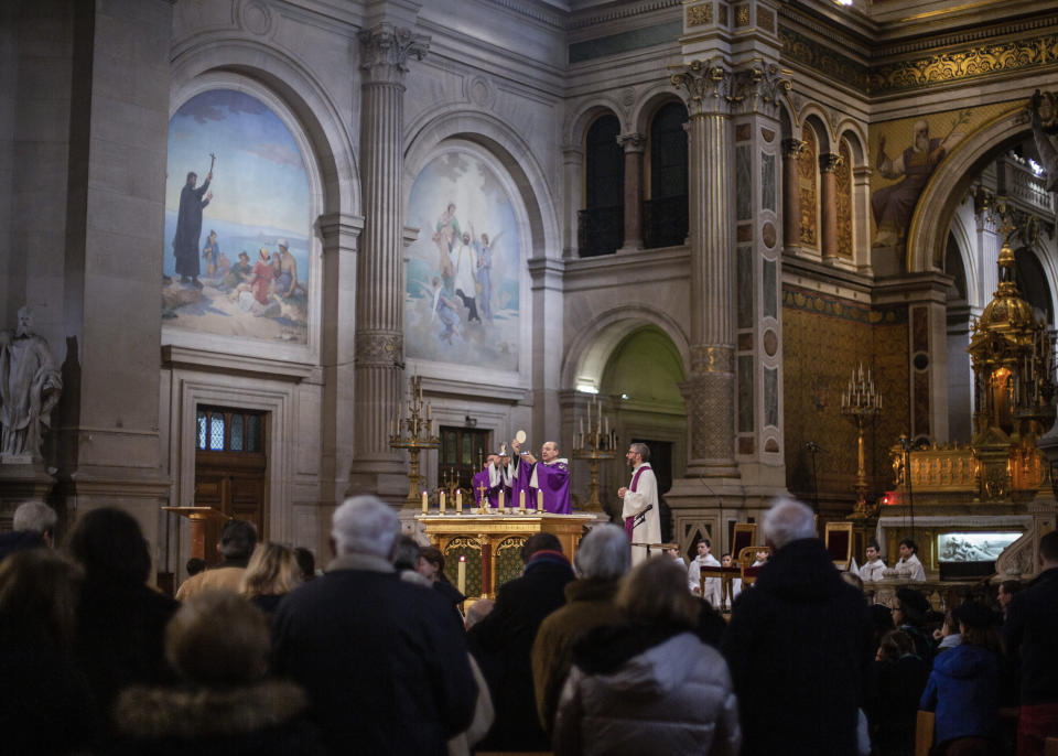 A priest prepares to give the Holy Communion to faithful during a Mass celebrated at Saint Francois Xavier church in Paris, France, Sunday, March 1, 2020. The archbishop of Paris is asking all of the French capital's parish priests to change the way they administer communion to counter the spread of the coronavirus. It said a Paris priest tested positive for the virus on Friday after returning from Italy. (AP Photo/Rafael Yaghobzadeh)