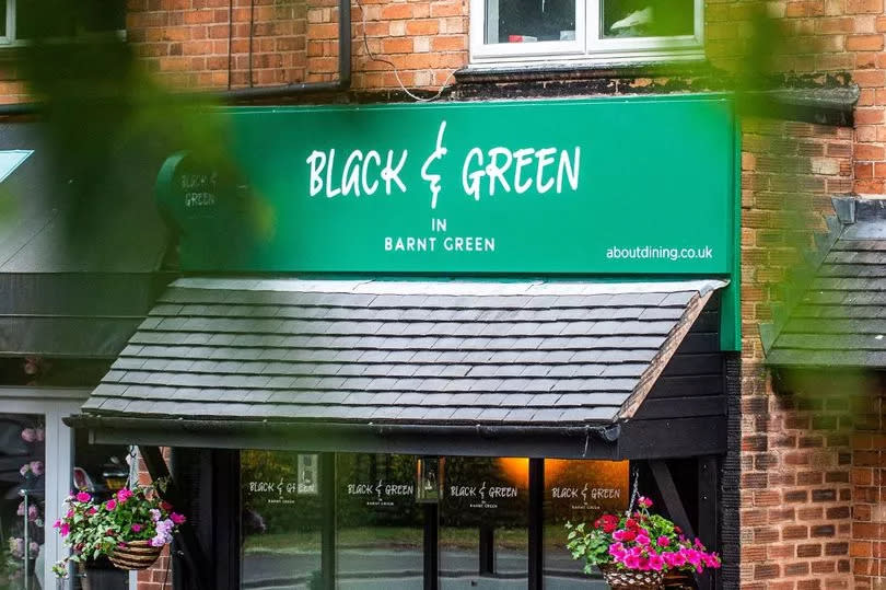 Red -ricked building with a green sign with the name of the restaurant: 'Black & Green in Brant Green'