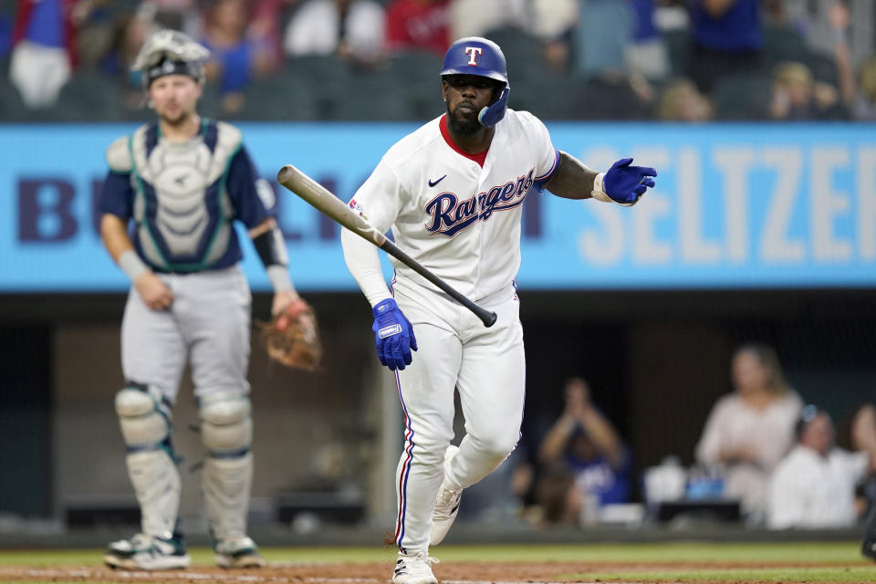 Texas Rangers' Adolis Garcia, right, tosses his bat in front of Seattle Mariners catcher Cal Raleigh, left, after hitting a three-run home run during the fourth inning of a baseball game in Arlington, Texas, Saturday, June 4, 2022. Rangers' Marcus Semien and Mitch Garver also scored on the play. (AP Photo/LM Otero)