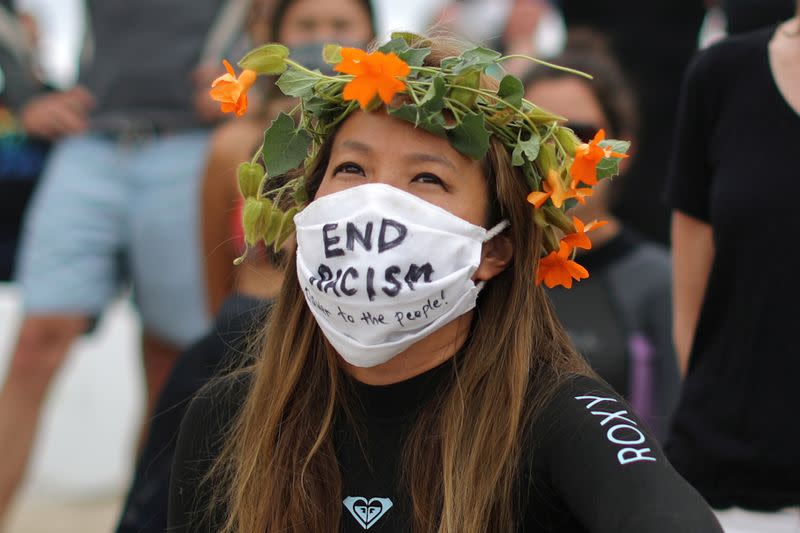 A woman listens to a speaker at The Black Girls Surf paddle-out in memory of George Floyd,