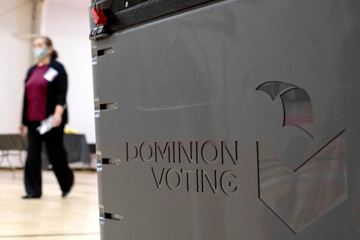 A worker passes a Dominion Voting ballot scanner while setting up a polling location at an elementary school in Gwinnett County, Georgia (AP)