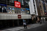 People wearing face masks walk past a Uniqlo store in Beijing