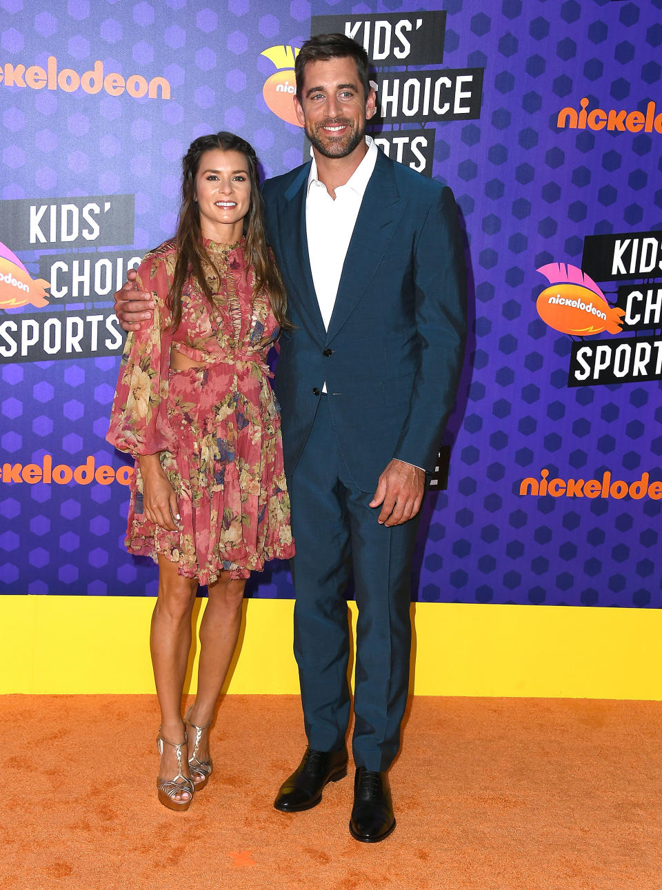 Two people smiling, wearing semi-formal attire, at a Nickelodeon event
